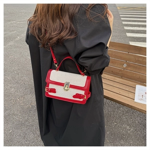 Close-up of contrast linen crossbody bag with red leather trim and gold twist lock