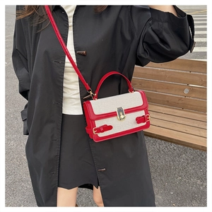 Detailed view of color-block canvas crossbody bag with red trim and gold metal lock