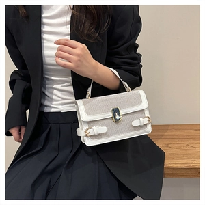 Detail of a chic cream crossbody bag with gold buckle and textured fabric finish