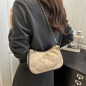 Elegant beige quilted shoulder bag with gold chain strap shown on model in warm indoor setting