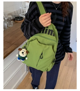 Detalle de mochila verde resistente al agua con letras impresas y colgante de perrito