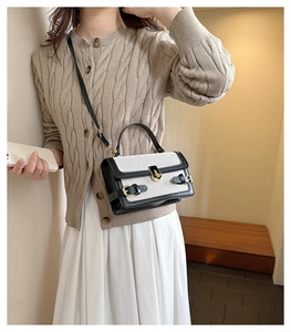 Detail of color-block linen handbag with gold buckle shown on a stylish model