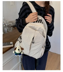 Detalle de la mochila de nailon blanco crema con gran capacidad y colgante de perrito