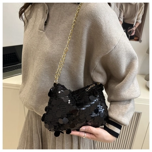 Close-up of black sequin texture on evening bag with delicate gold chain strap