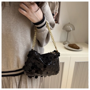 Close-up of black sequined bag with gold chain strap in a soft lifestyle setting
