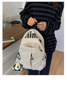 Detalle de la mochila de nailon resistente al agua con colgante de perro y letras