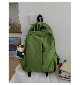 Detailed view of lightweight green nylon backpack with cute panda charm on a sofa