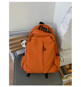 Bright orange travel backpack detail with front zipper and cute puppy plush charm