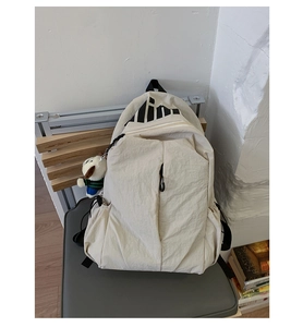 Detail of beige nylon travel backpack with geometric patterns and a cute dog plush charm