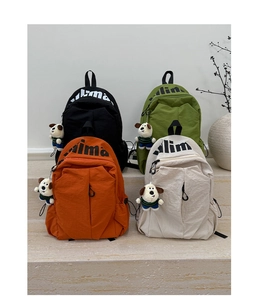 Macro shot of stylish nylon backpacks in four colors with cute dog charms for travel