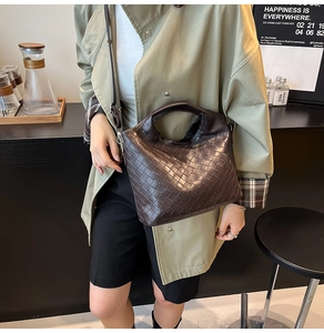 Detail view of dark brown woven leather bucket bag with top handle and crossbody strap