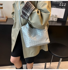 Close-up of silver woven leather tote bag featuring metallic texture and adjustable strap