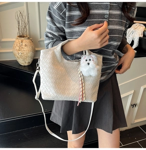 Detail of woven texture tote bag with a cute plush dog pendant on a model in daily life