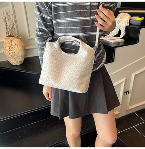Detail of off-white woven faux leather bucket bag with top handle and shoulder strap
