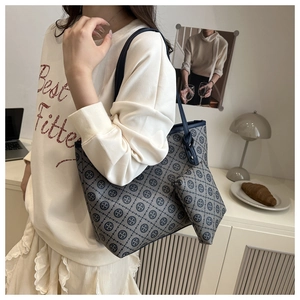 Detail shot of a large grey tote bag with monogram print and matching pouch on a model