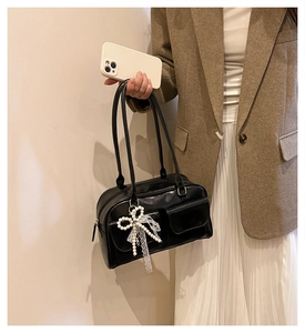 Détail du sac Boston en cuir noir avec breloques nœud en perles et doubles poches rétro