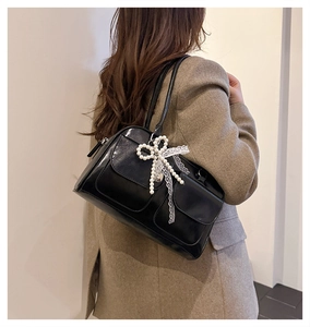 Détail du sac à bandoulière noir avec nœud en perles et dentelle sur un mannequin élégant