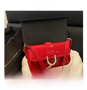 Detail of red patent leather shoulder bag with a large golden D-shaped horseshoe buckle