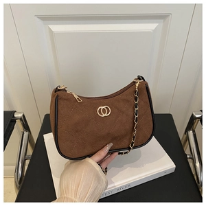 Detail of brown suede shoulder bag featuring diamond quilting and gold double ring clasp