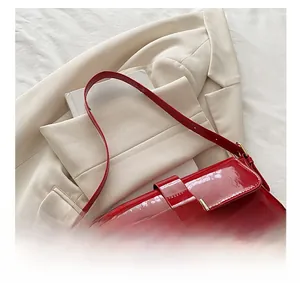 Macro detail of red patent leather texture and gold horseshoe buckle on handbag