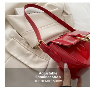 Detail of red patent leather shoulder bag showing adjustable strap and gold buckle