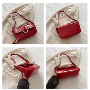 Detail view of red glossy leather shoulder bag with large golden D-ring buckle hardware