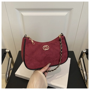 Detail of burgundy quilted suede shoulder bag with gold metal logo and chain strap