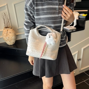 Creamy white woven bucket bag with plush charm and crossbody strap for women
