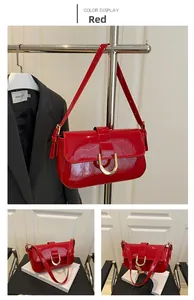 Detail of red patent leather shoulder bag with vintage gold horseshoe buckle and strap