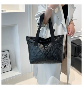 Detail of quilted black tote bag featuring bow patterns and wide shoulder strap