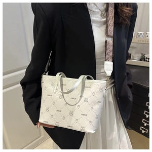 Detail of white bucket bag featuring cartoon prints and geometric patterned shoulder strap