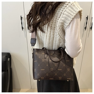 Detail of a brown plaid tote bag with wide geometric strap and cartoon bear pattern