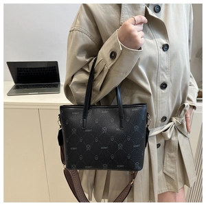 Detail of black embossed tote bag with brand lettering and detachable wide shoulder strap