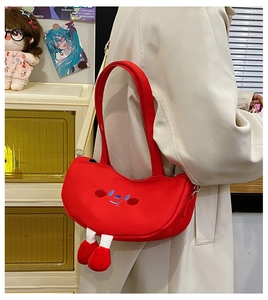 Detail of red canvas shoulder bag with creative hanging legs and cute facial embroidery