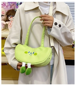 Detail view of a green canvas tote with cute cartoon face embroidery and plush legs