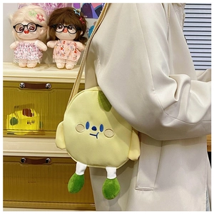 Detail of yellow canvas crossbody bag featuring embroidered face and green plush legs