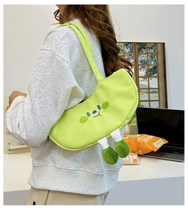 Detailed view of creative green cartoon shoulder bag with cute plush legs on a desktop