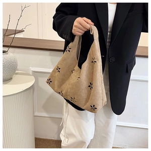 Detail of light khaki knitted tote bag with black hollow floral patterns and single handle