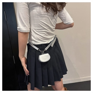 Detail of a metallic silver mini waist bag with a semicircular design on a fashion model
