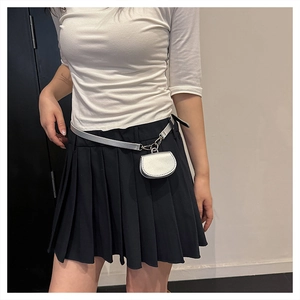 Detail of silver mini pouch on matching belt paired with a black pleated skirt