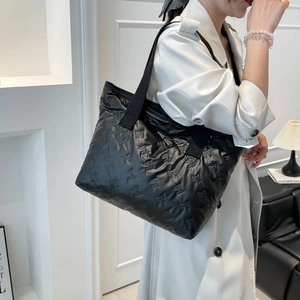 Black quilted puffer tote bag with embossed bow patterns and spacious interior design