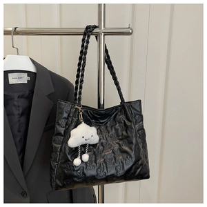 Detail of black quilted tote bag with bear embossing and braided shoulder straps