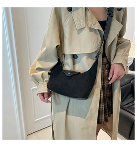 Detail of black suede hobo bag with silver buckle worn with a classic trench coat