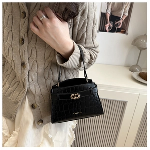 Detail of black faux leather mini bag with crocodile pattern and golden circular clasp