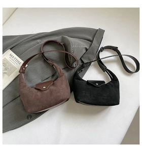 Macro detail of brown and black suede crescent bags with metal buckles and leather straps