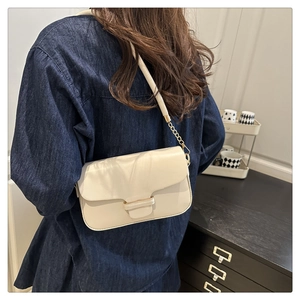 Chic cream white leather shoulder bag with gold clasp and chain strap on a model