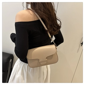 Detail of beige leather crossbody bag with flap closure and gold chain strap on shoulder