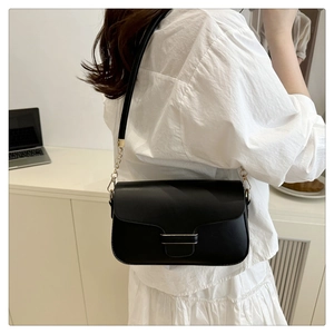 Detail of a black PU leather crossbody bag with metal chain strap and flap closure