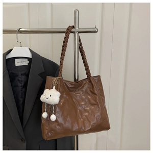Close-up of brown embossed bear pattern tote bag with woven strap and cloud charm