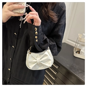 Detail of white handbag with large bow decoration and gold chain strap close-up